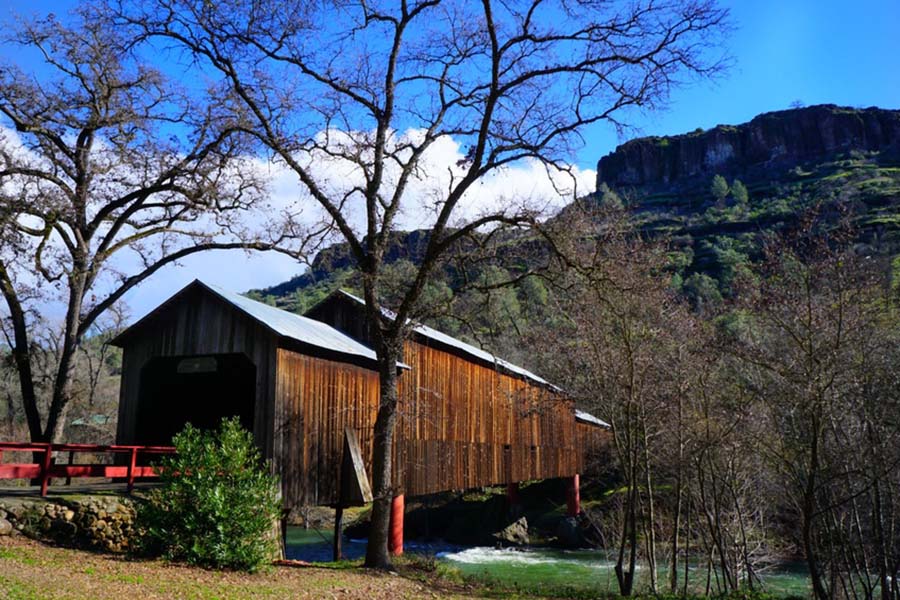 About Our Agency - View of the Honey Run Covered Bridge Over a Creek Next to a Mountain in Chico California